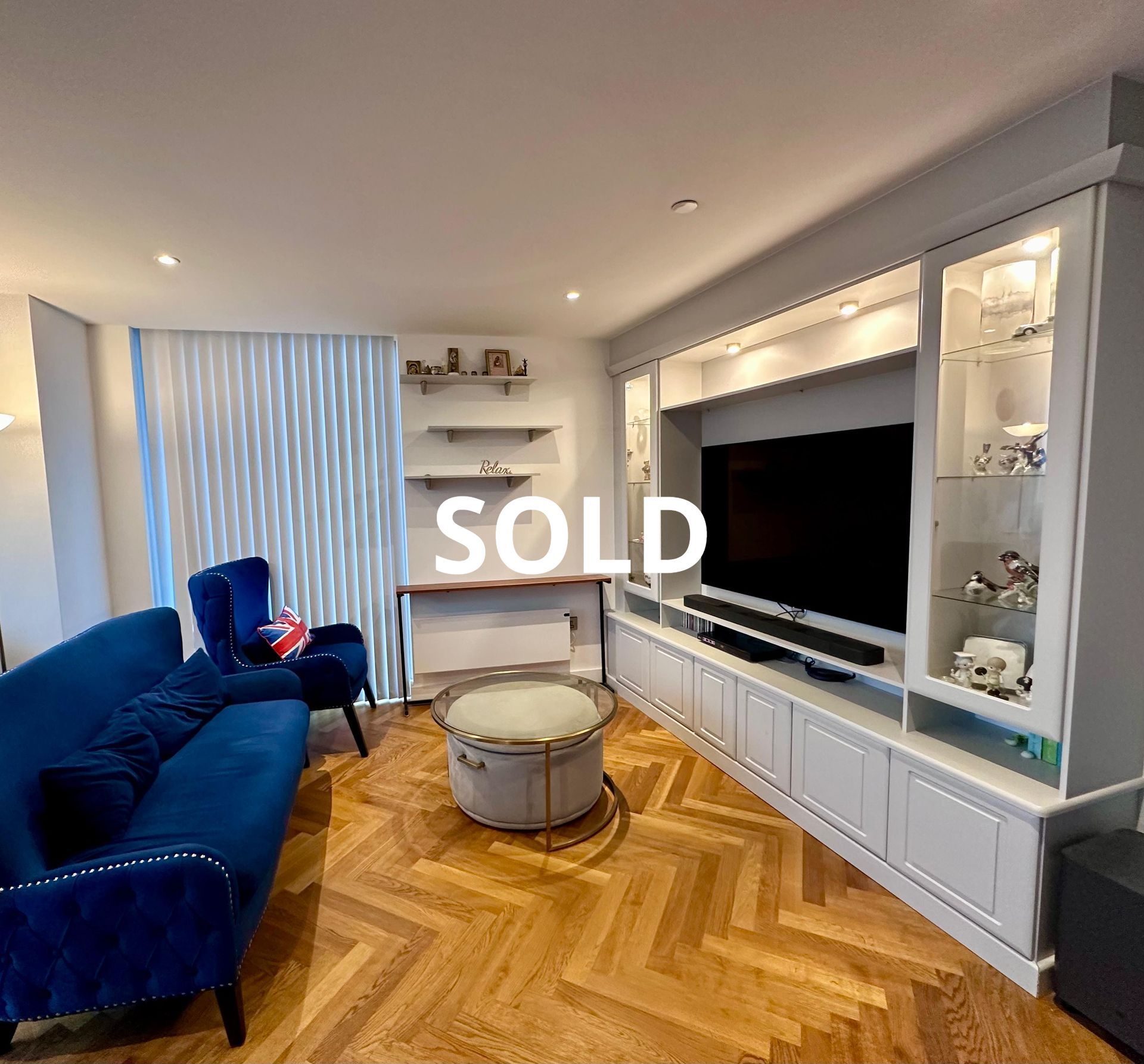 Living room with blue sofa, built-in entertainment center, parquet floors; 