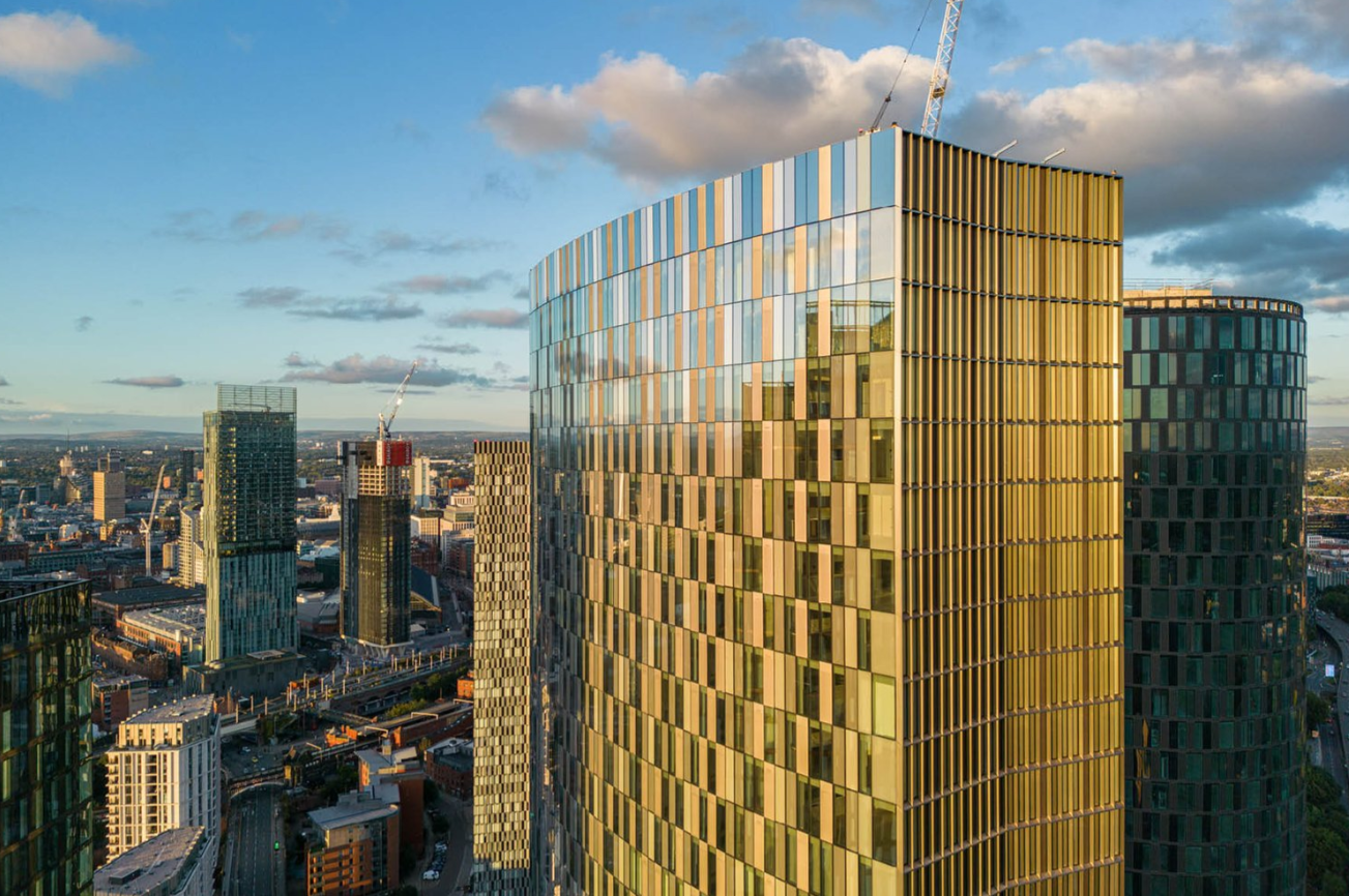 Skyscrapers with gold-toned glass facades against a city skyline.