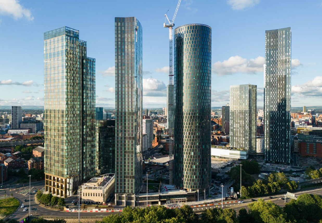 High-rise glass buildings against a clear blue sky, with a construction crane visible, in an urban setting.