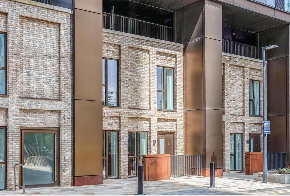 Brick building exterior with bronze columns, windows, and a walkway.