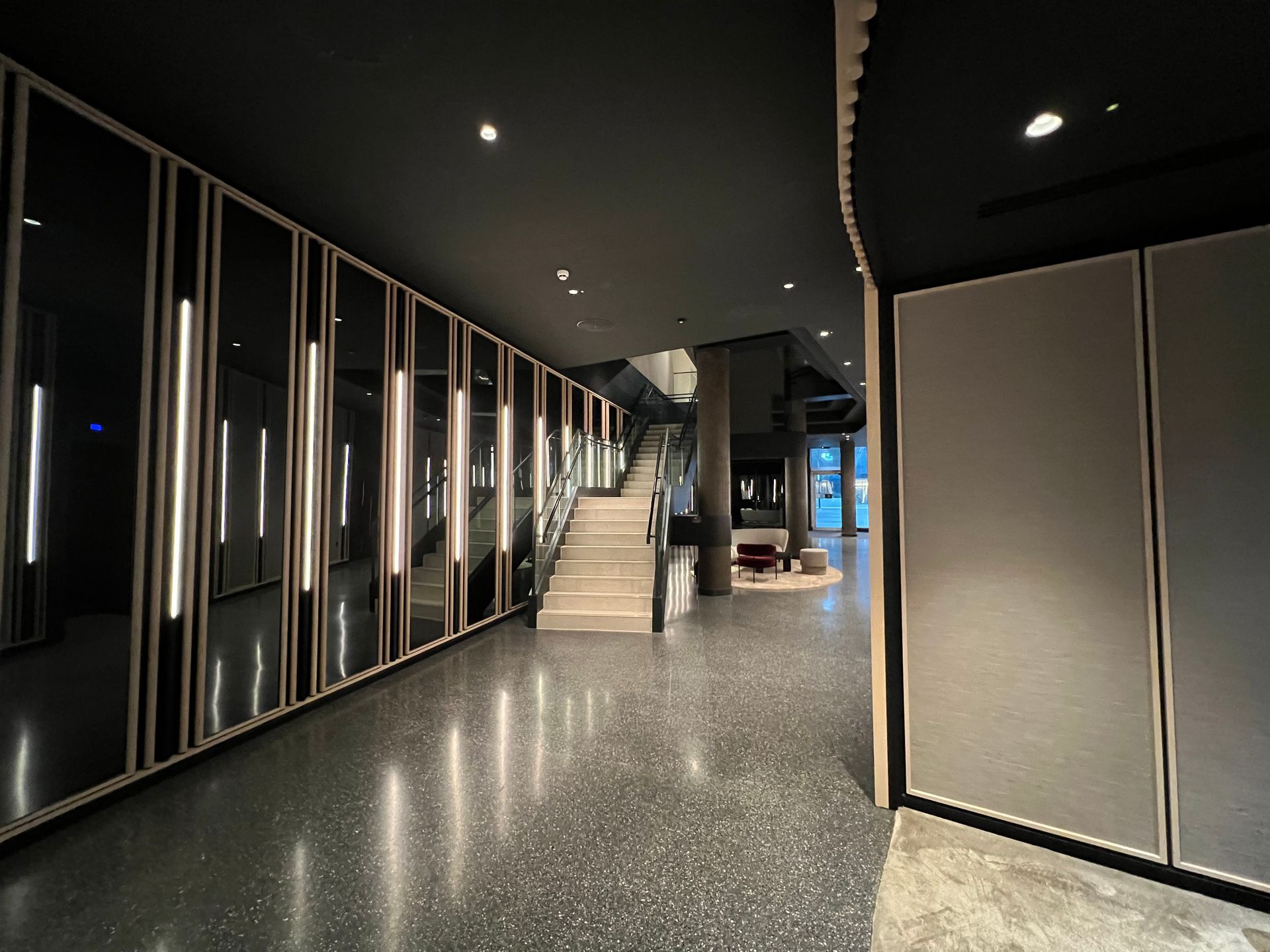 Interior hallway with reflective panels, recessed lights, and stairs.