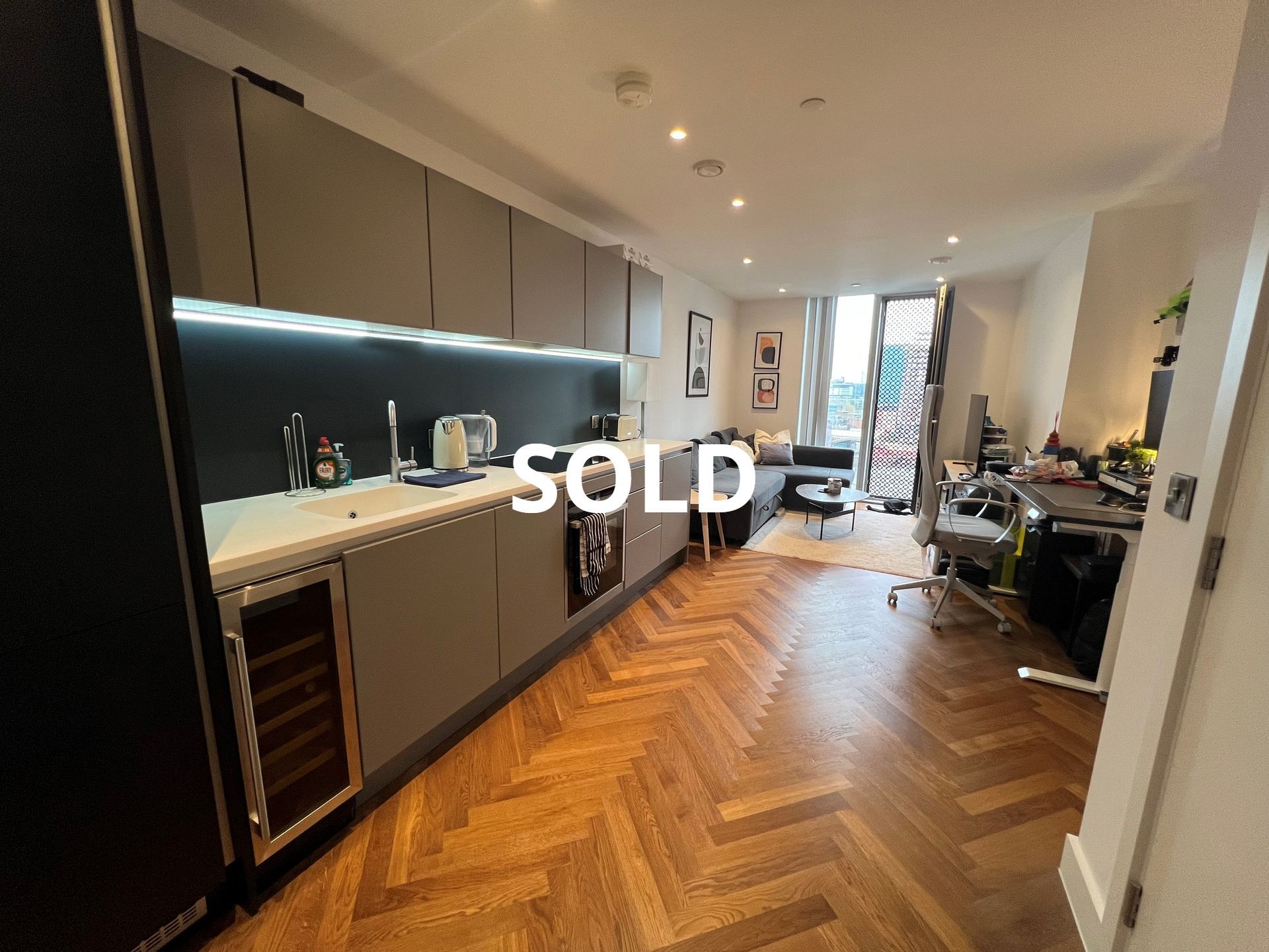 Modern apartment interior with kitchen, living area, and wooden floors; 