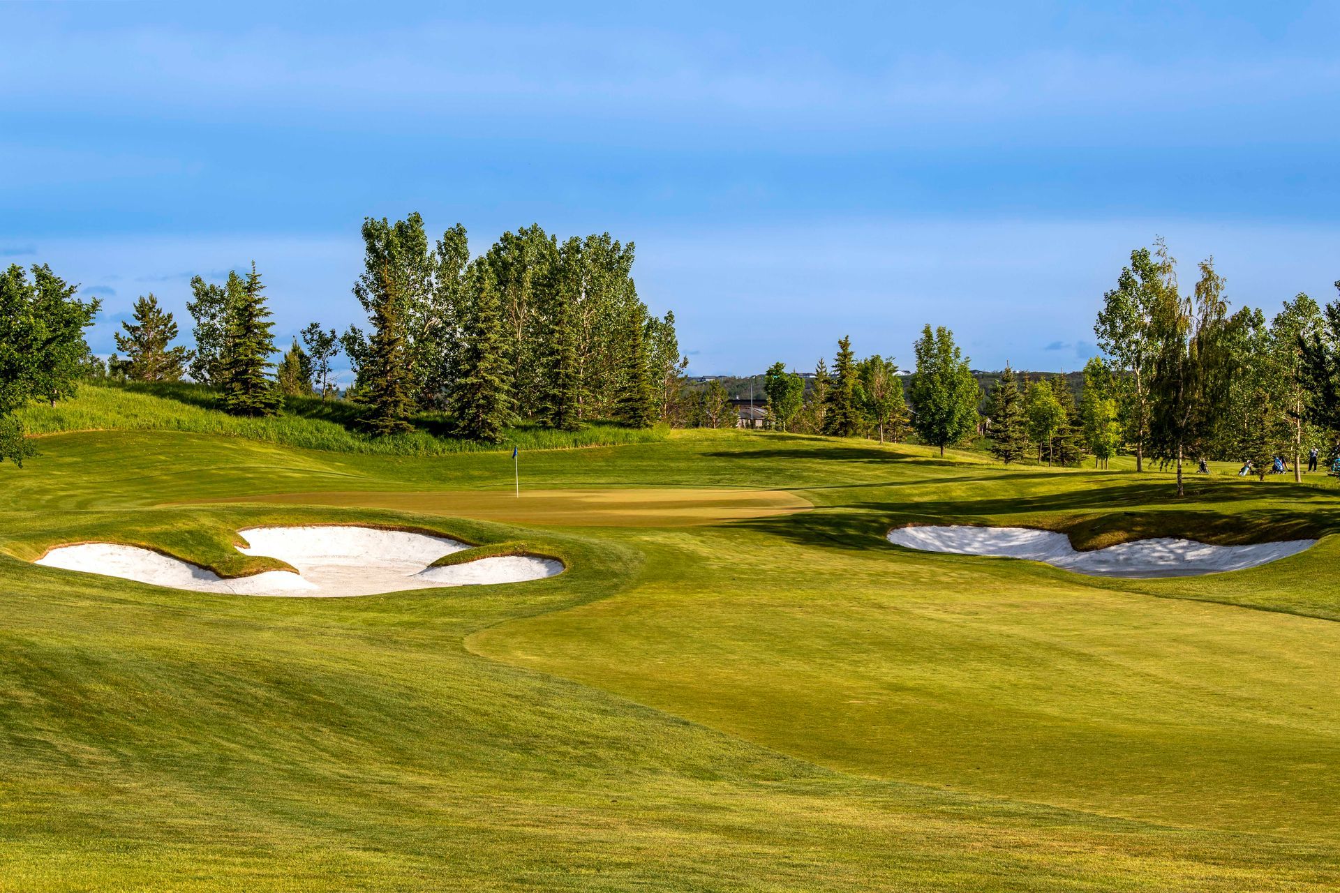 Golfer swinging club on green course with rainbow in background.