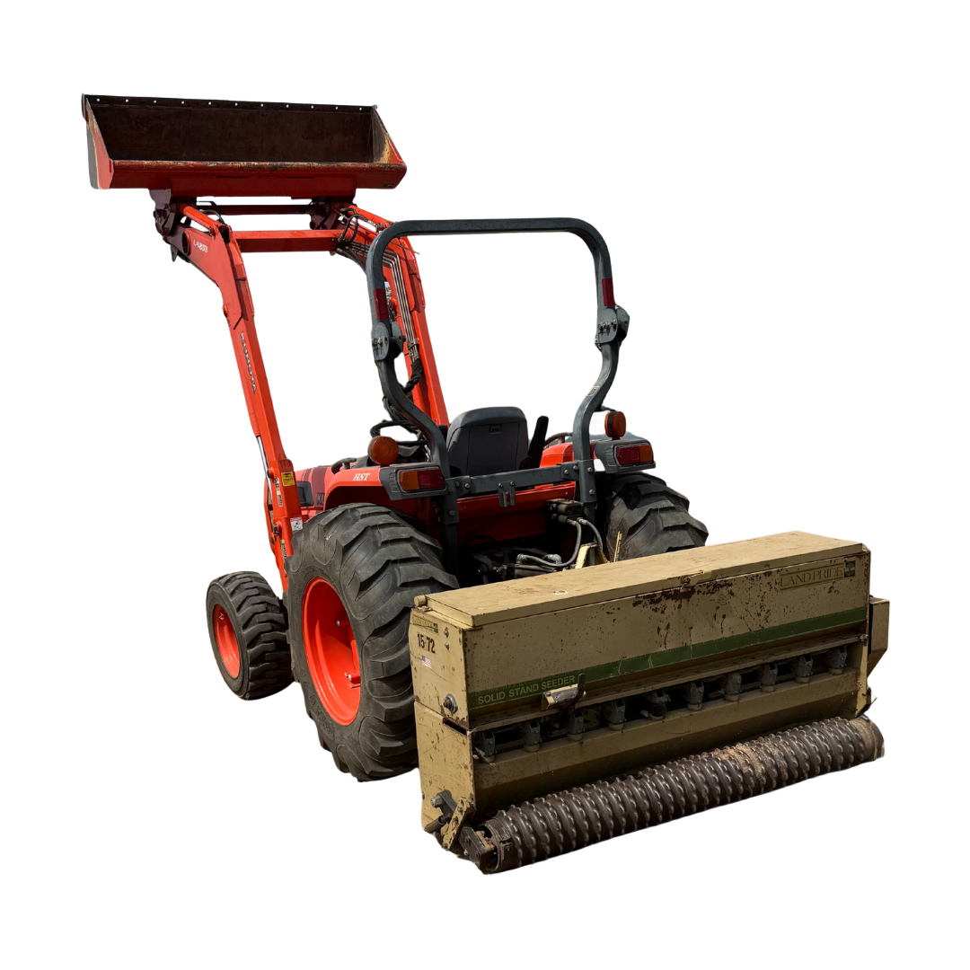 Orange tractor with a front-end loader and a seeder attachment, ready for work outdoors.