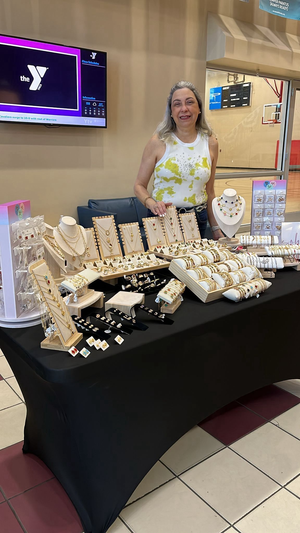 A woman is standing in front of a table filled with jewelry.