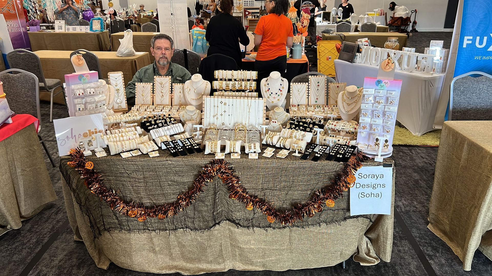 A man is sitting at a table with a lot of jewelry on it.