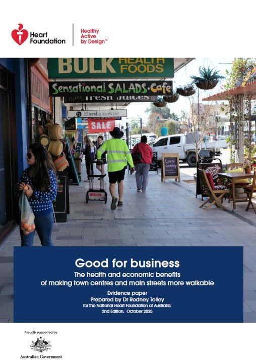 Shoppers and an outdoor dining setting on a main street. Business signs advertising healthy food