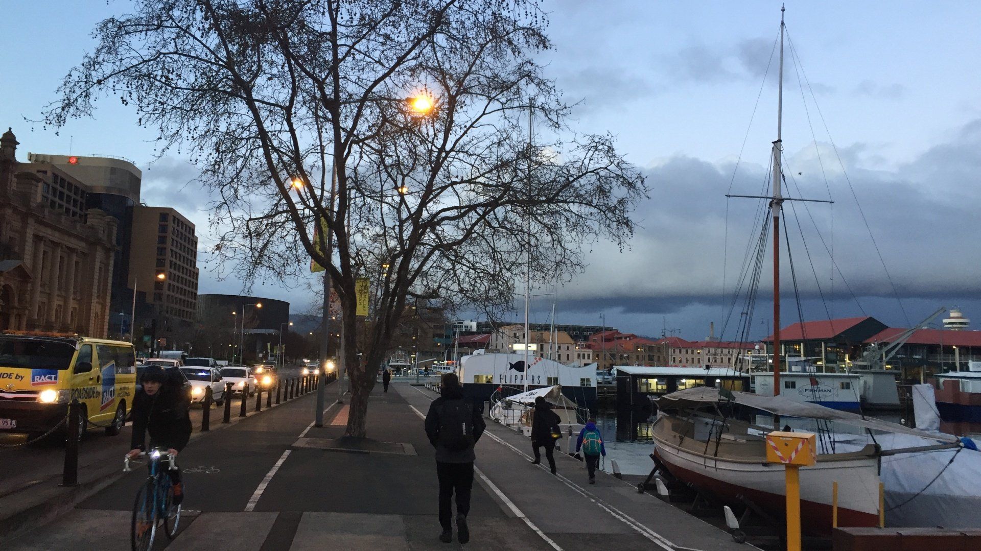 A group of people are walking down a sidewalk in a city