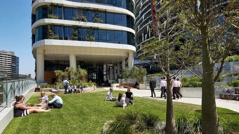 A group of people are sitting on the grass in front of a building.