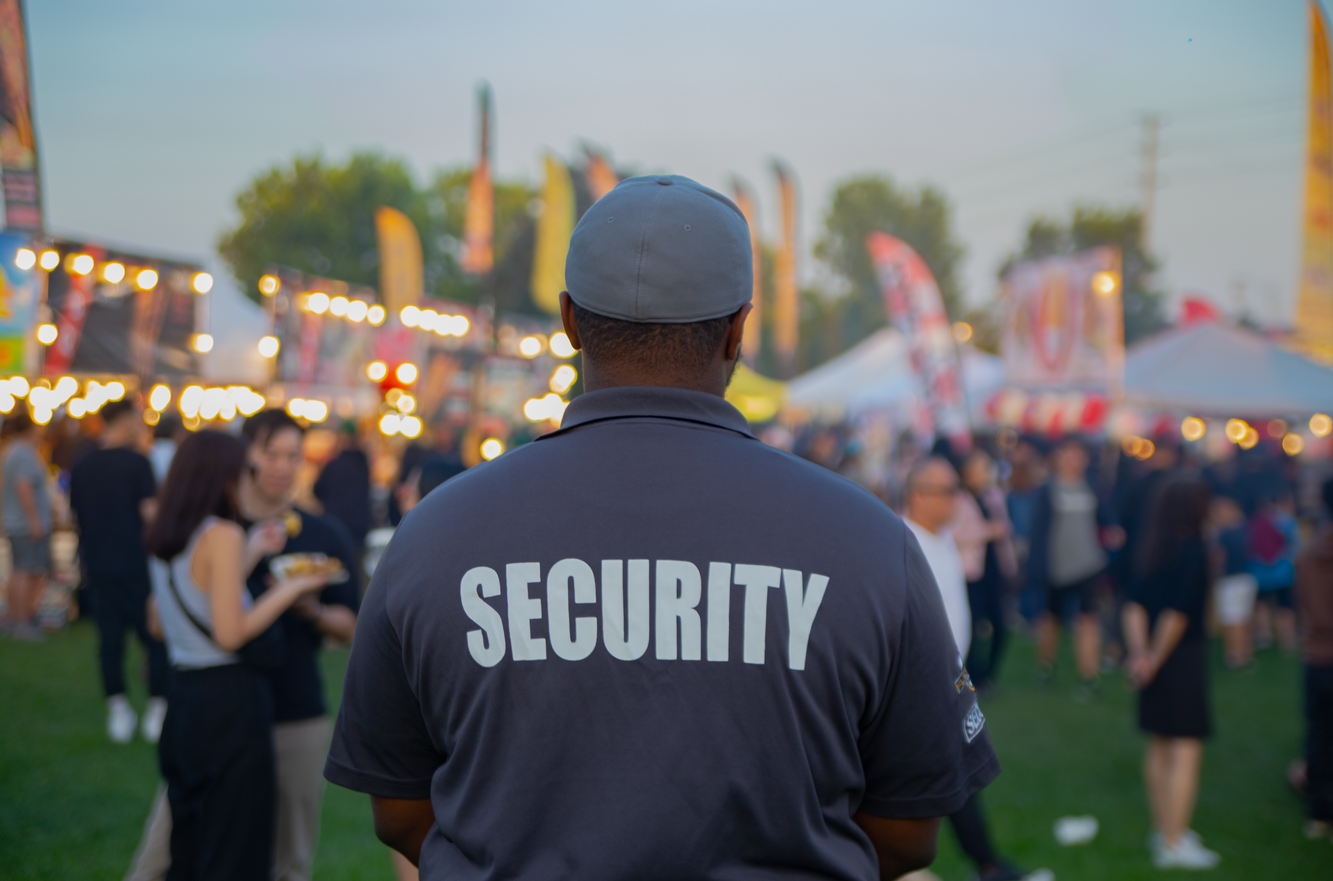 A security guard is standing in front of a crowd of people at a festival.