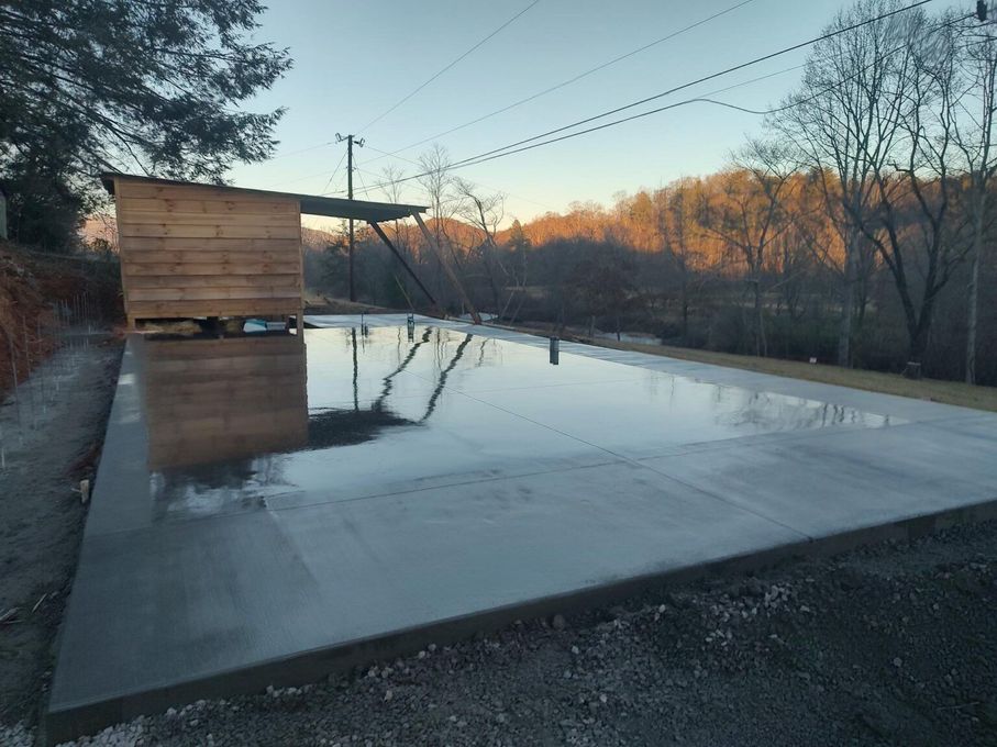 A concrete driveway with a wooden shed in the background