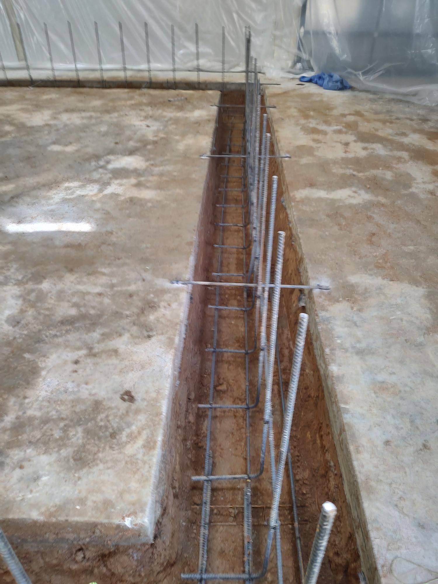 A trench is being filled with concrete and steel bars.