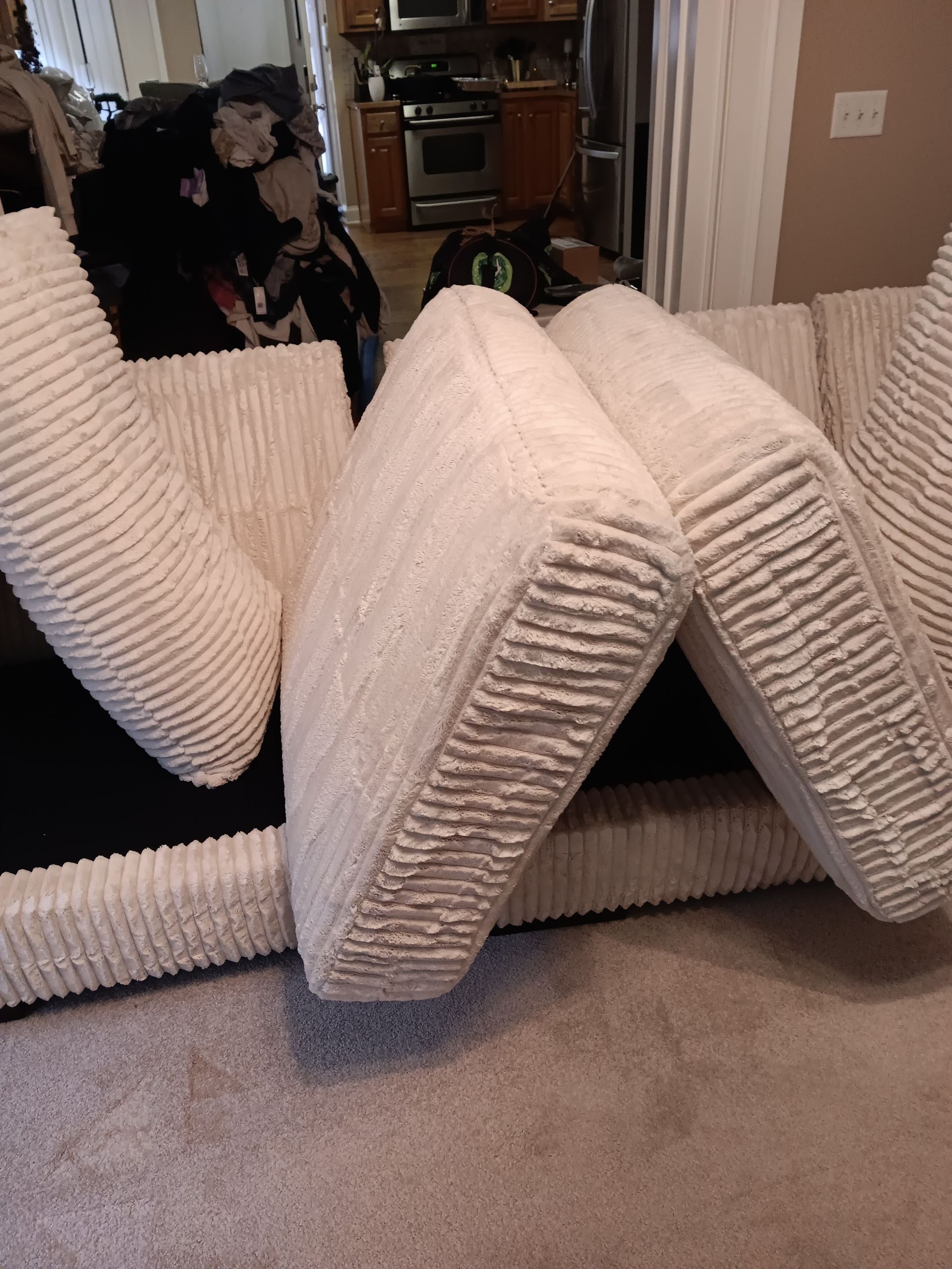 Beige corduroy sofa cushions, partially folded, indoors.