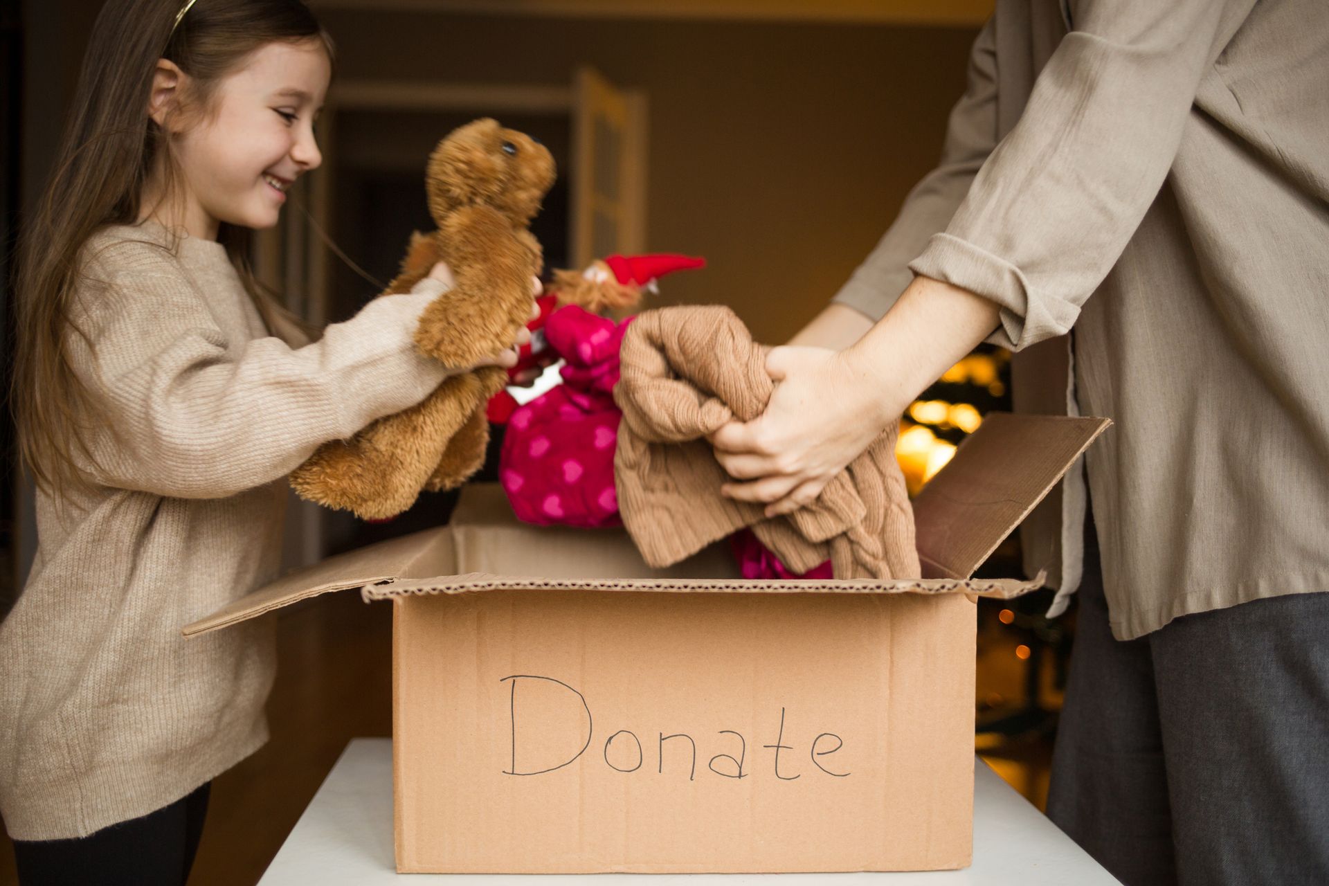 A young girl helping her parents fill a donation box.