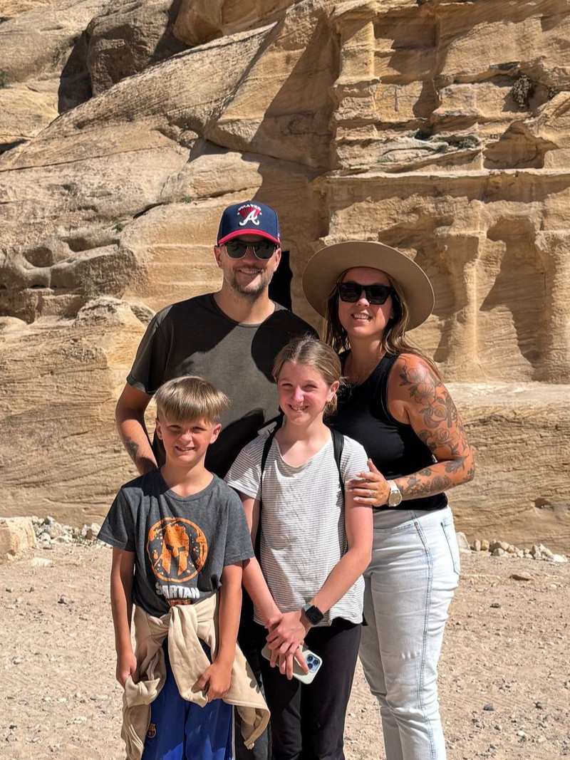 A family of four poses in front of ancient ruins in Jordan's Petra.