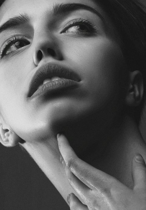 A black and white photo of a woman 's face with her hand on her chin.