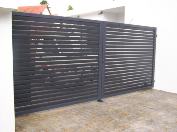 A black fence with a white wall behind it