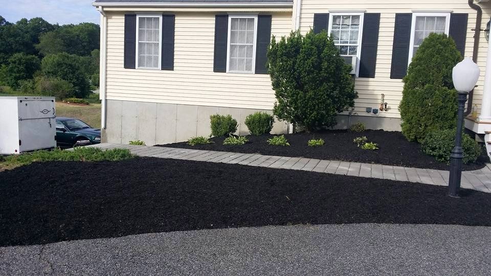 A house with black shutters and a walkway in front of it
