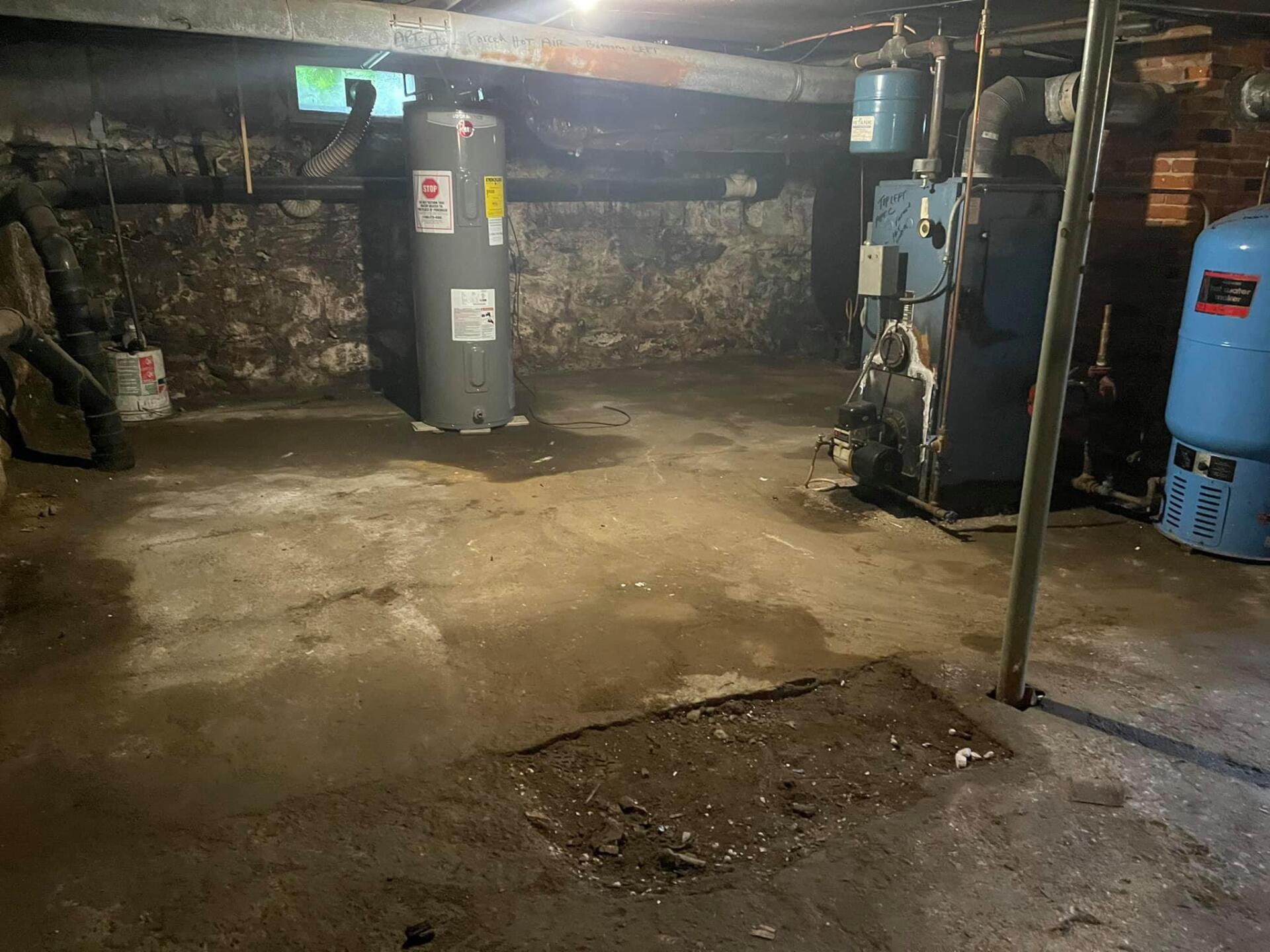A dirty basement with water heaters and pressure tanks