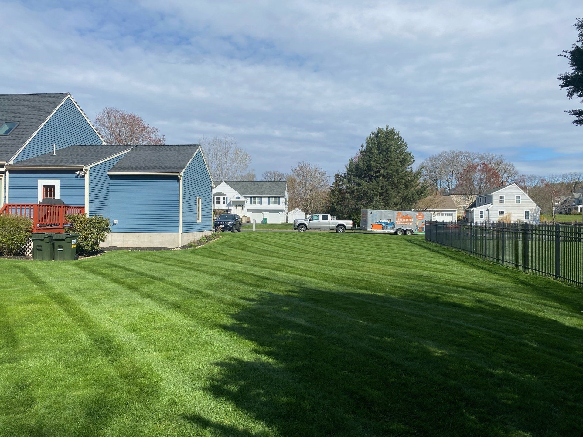 A lush green yard with a blue house in the background