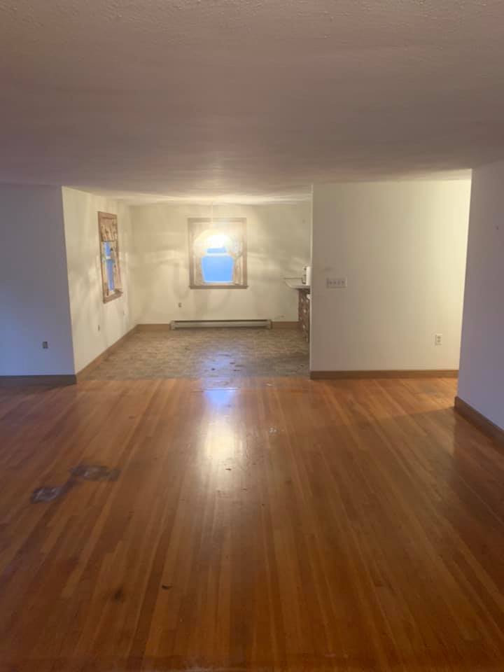 An empty living room with hardwood floors and a window.