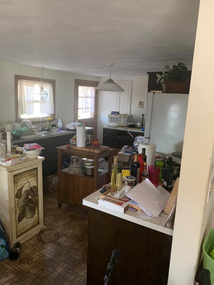 A kitchen with a lot of junk on the counters and counter tops.