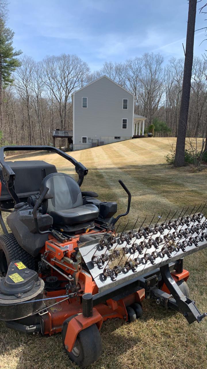 A lawn mower is parked in the grass in front of a house.