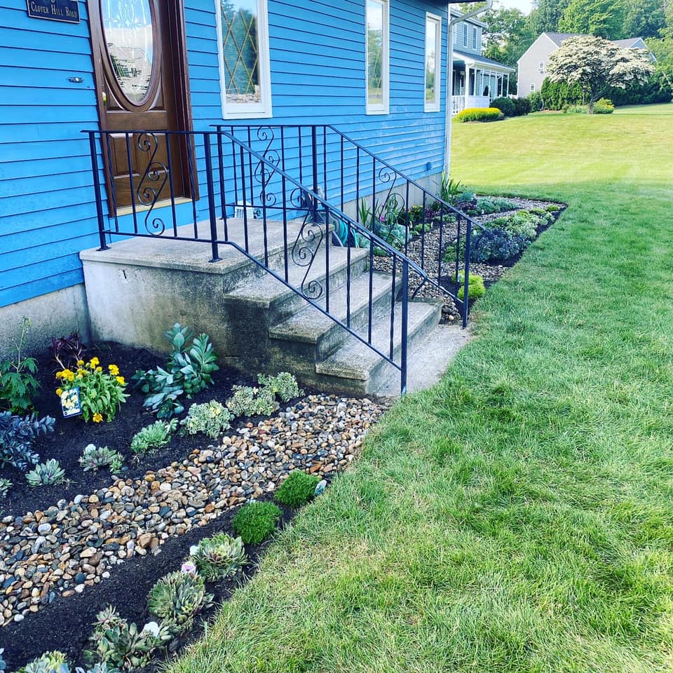 A blue house with a wrought iron railing and steps in front of it.