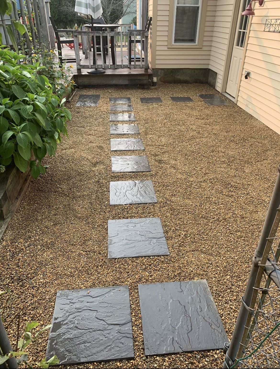 A stone walkway leading to a deck in a backyard.