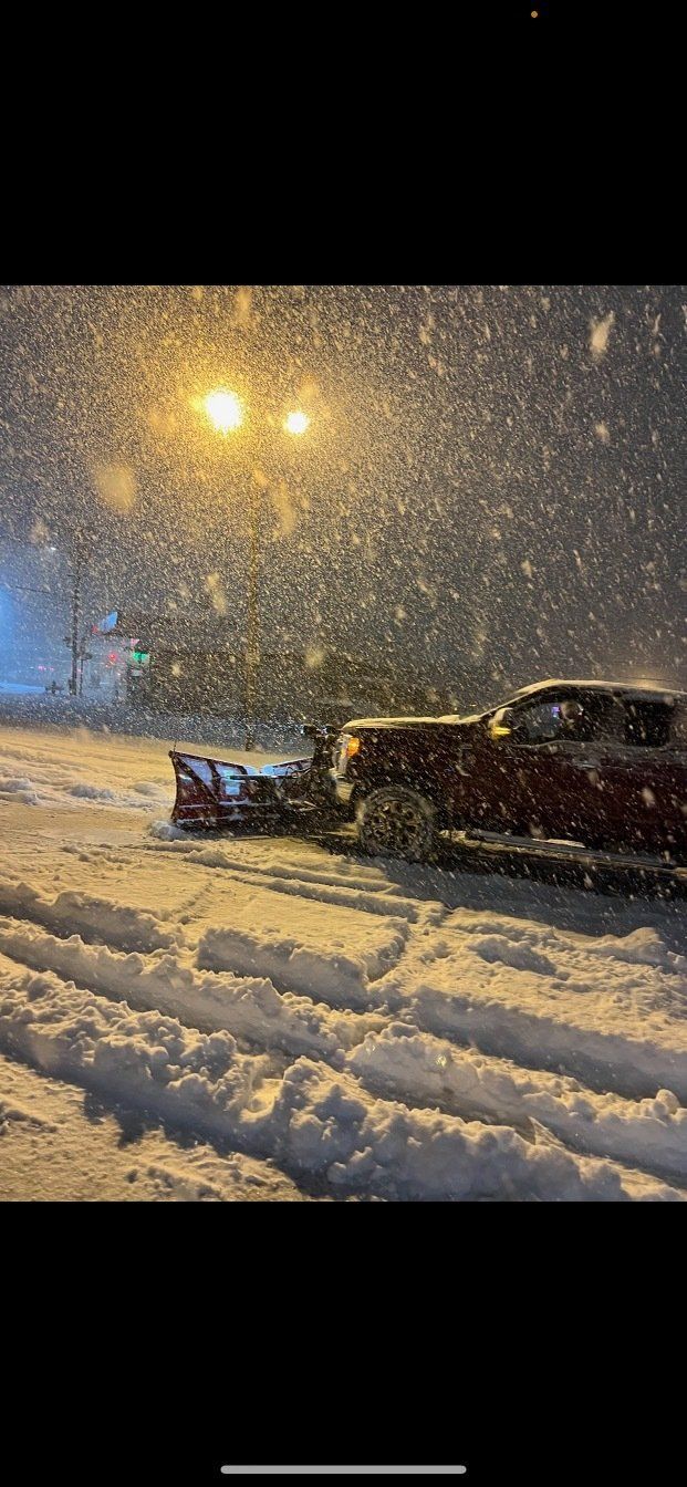 A truck is being plowed in the snow at night.