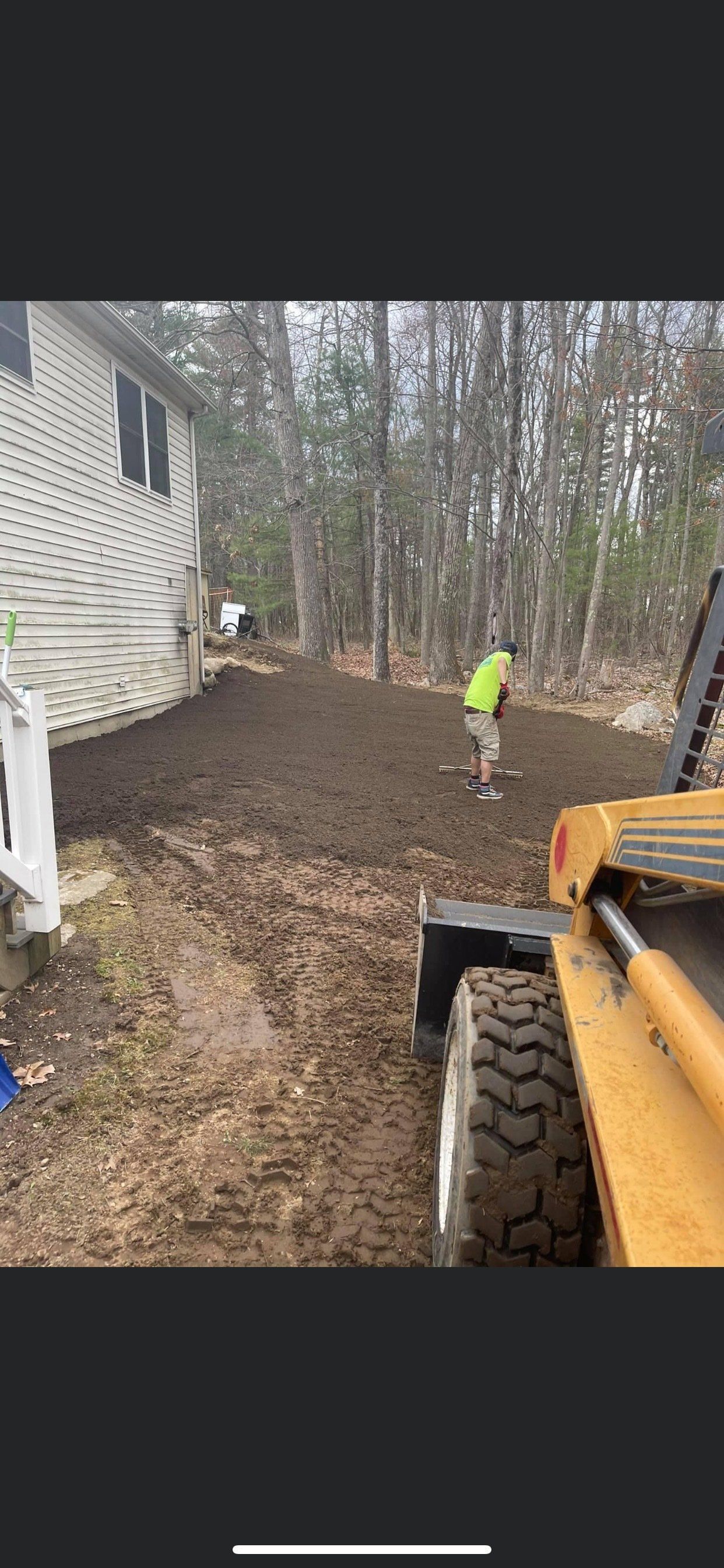 A man is standing next to a bulldozer in a yard.