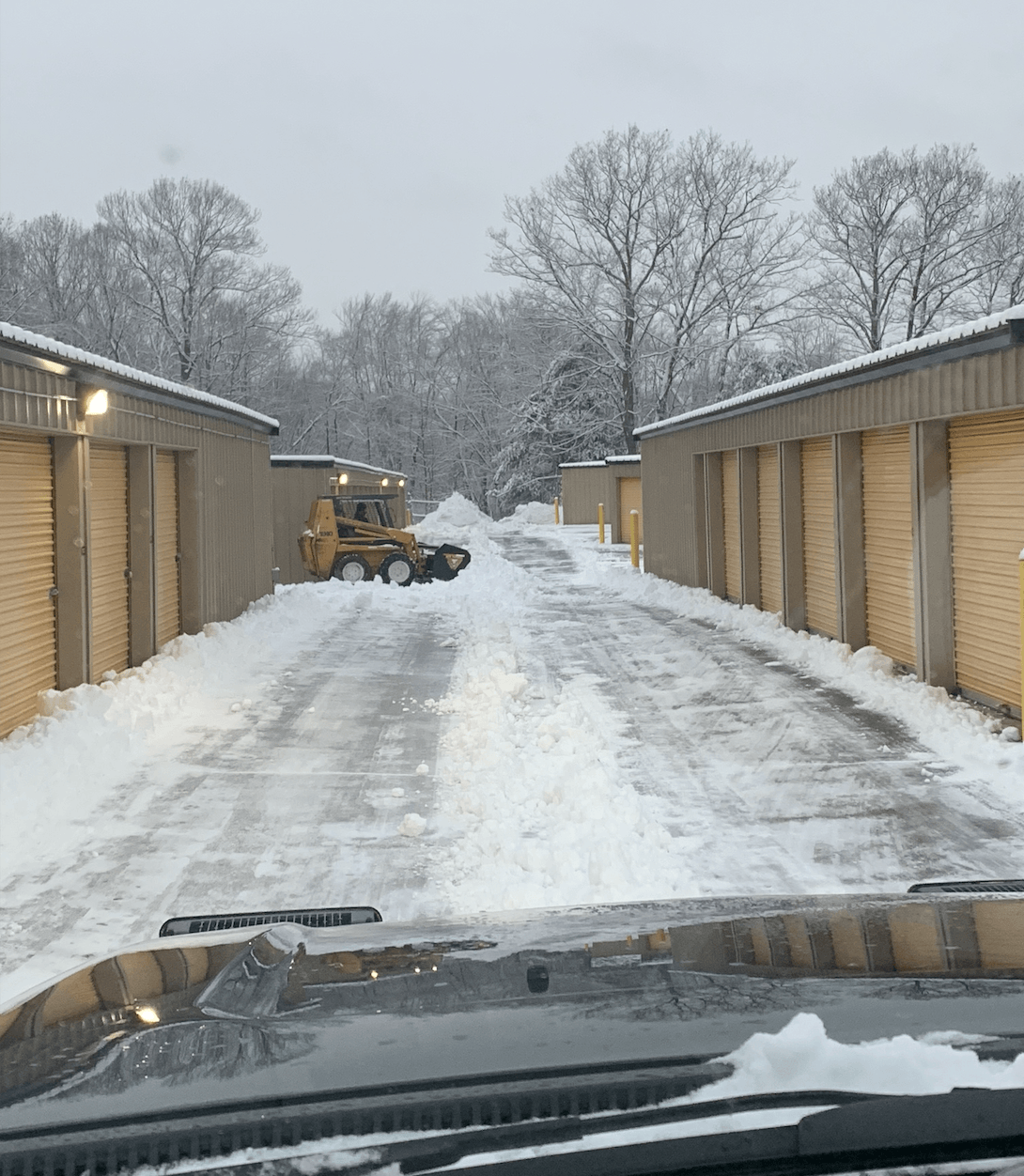 A snow plow is driving down a snowy road