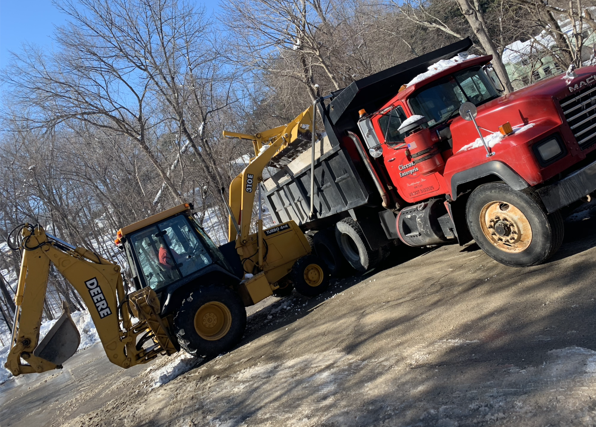A red dump truck is parked next to a yellow excavator.