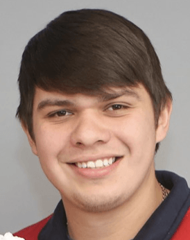 A young man in a red shirt is smiling for the camera. Zach Rodas