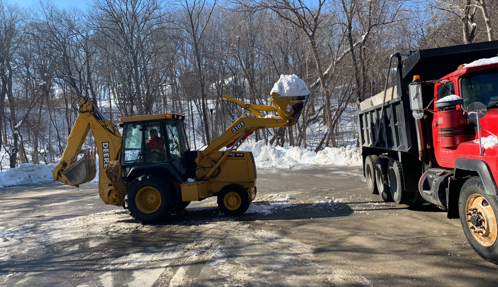 A bulldozer is loading snow into a dump truck.
