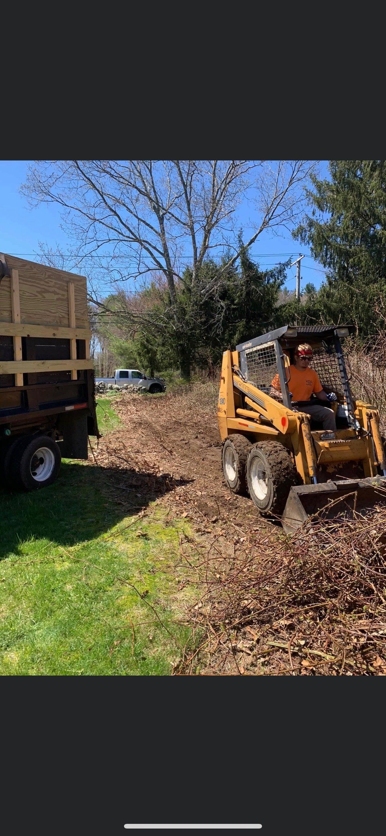A man is driving a small tractor through a pile of leaves.