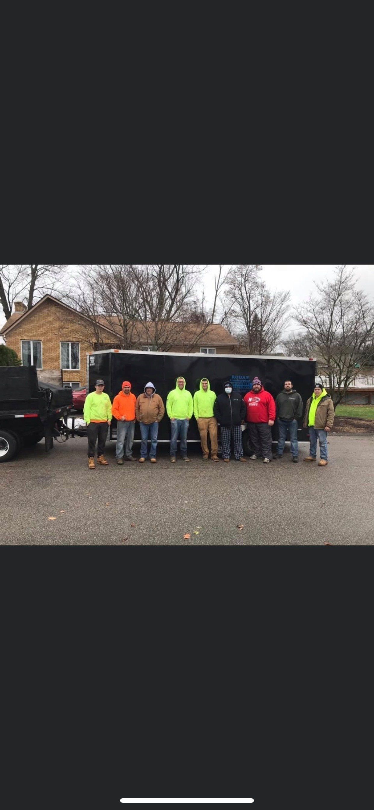 A group of men are standing in front of a truck in a parking lot.