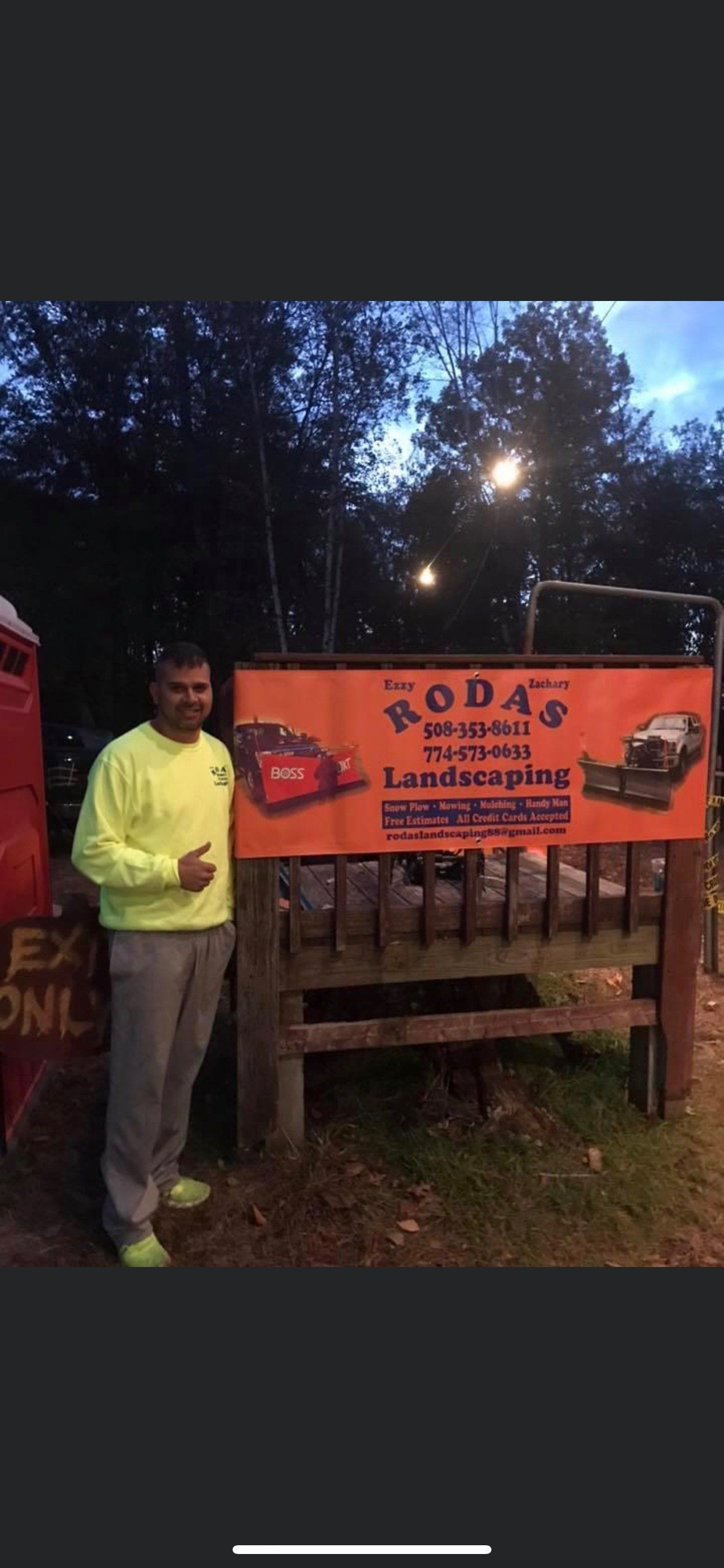 A man is standing in front of a large orange sign.