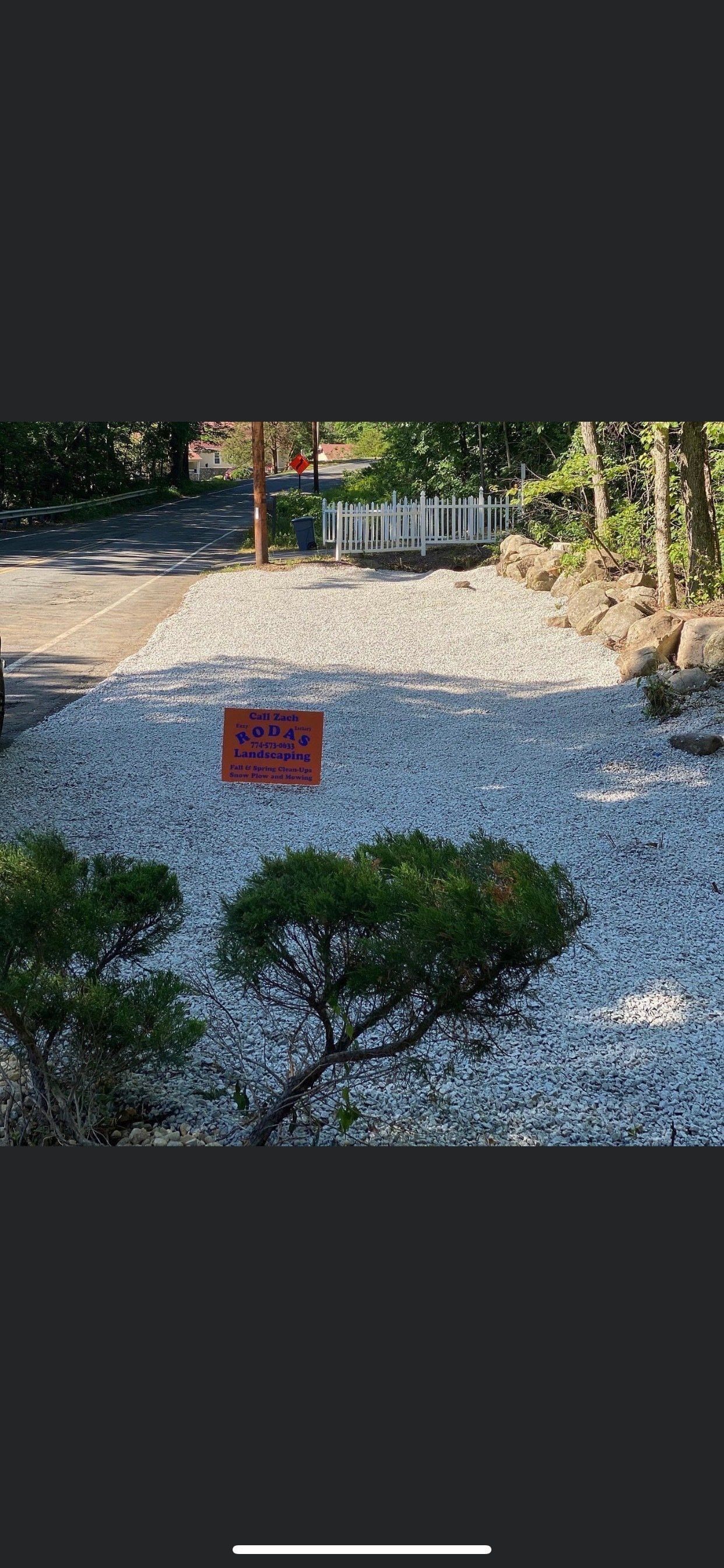 A sign is sitting on top of a pile of gravel in a garden.