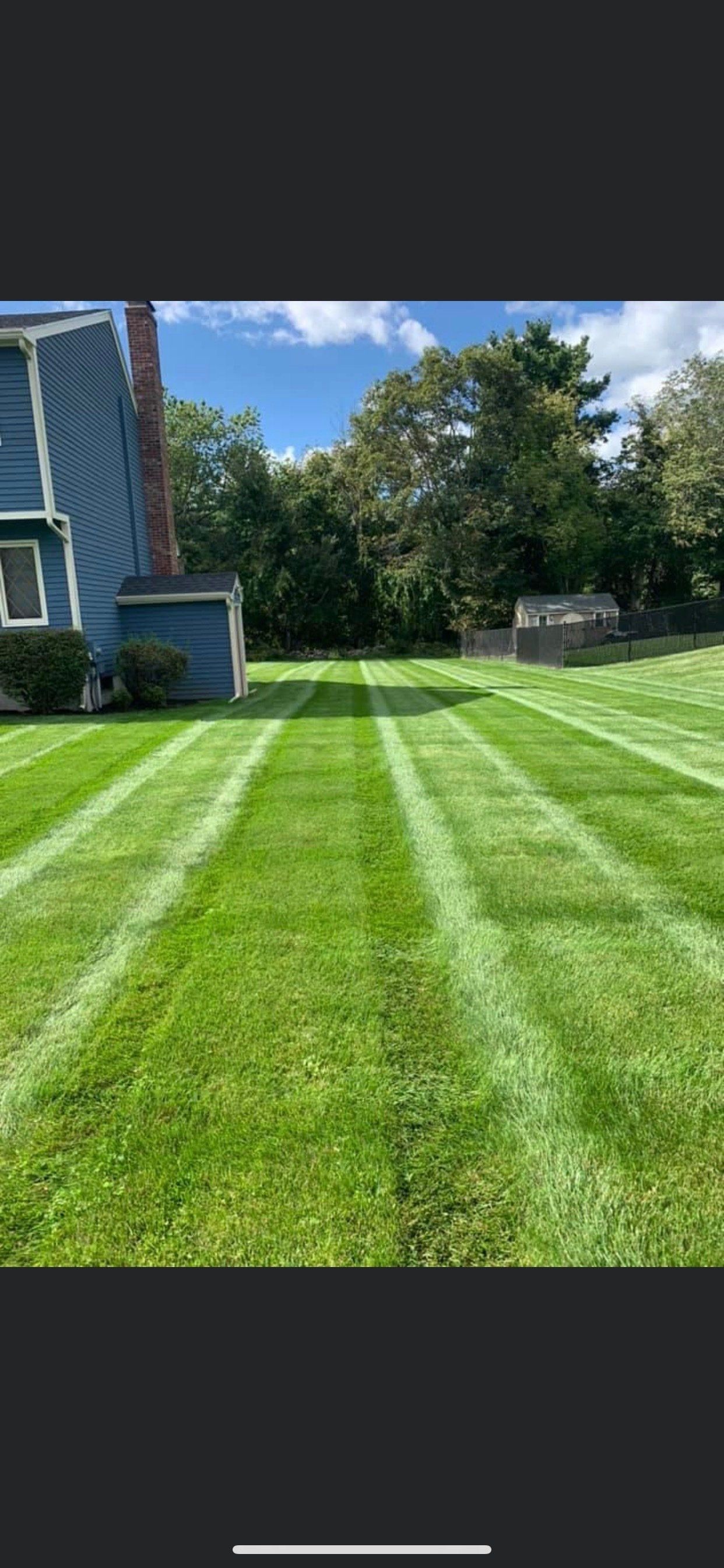 A lush green lawn with white stripes in front of a house.