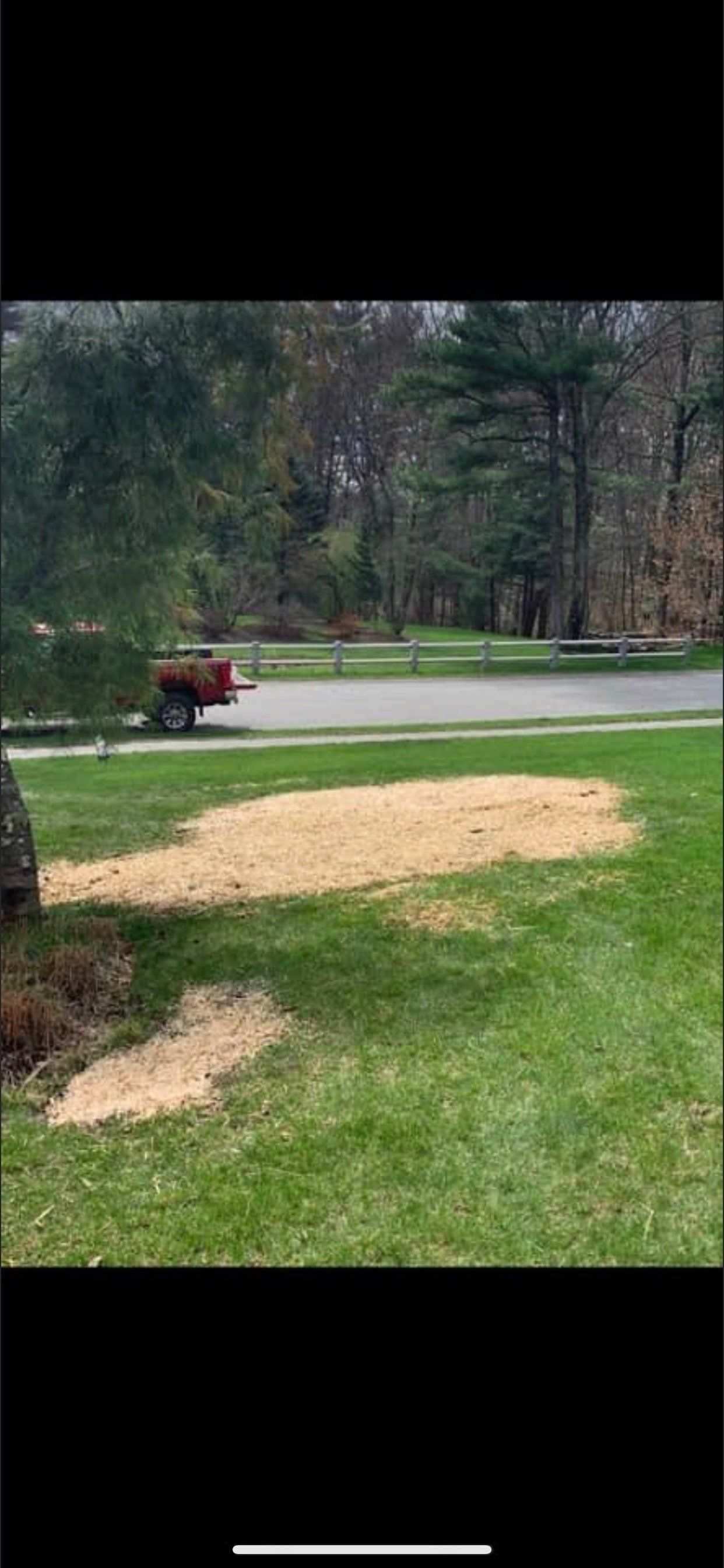 A red truck is driving down a road next to a grassy field.