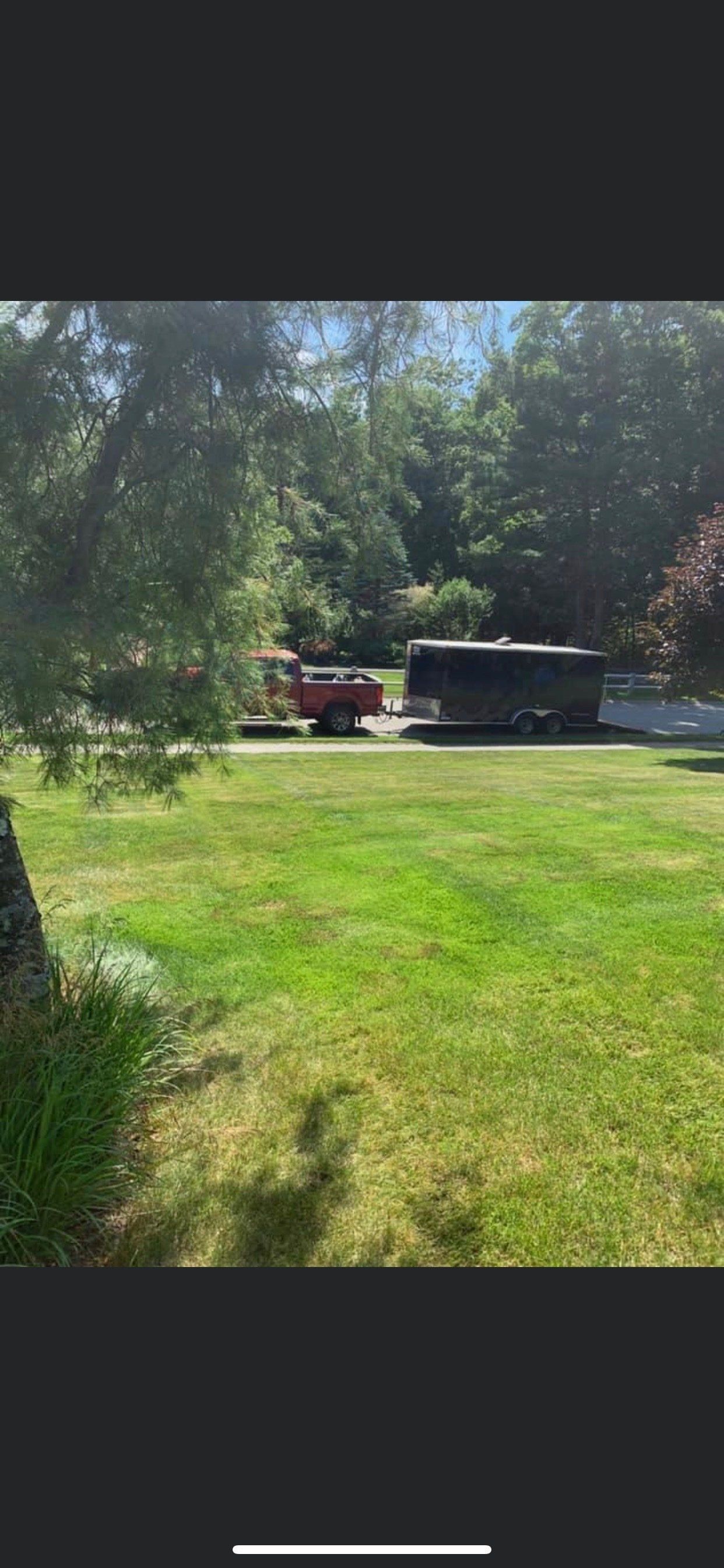 A truck and trailer are parked in a grassy field.