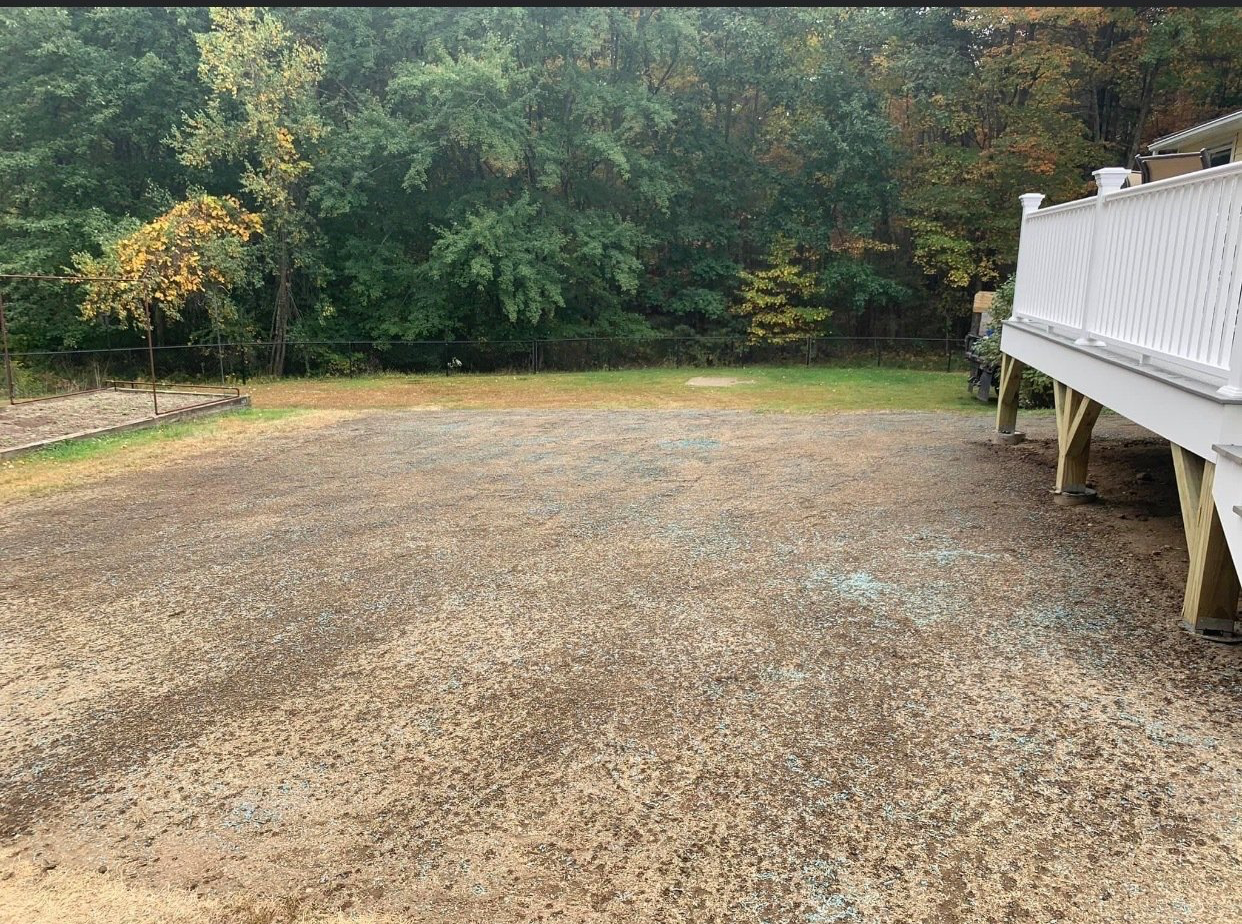 A gravel driveway with a white deck in the background