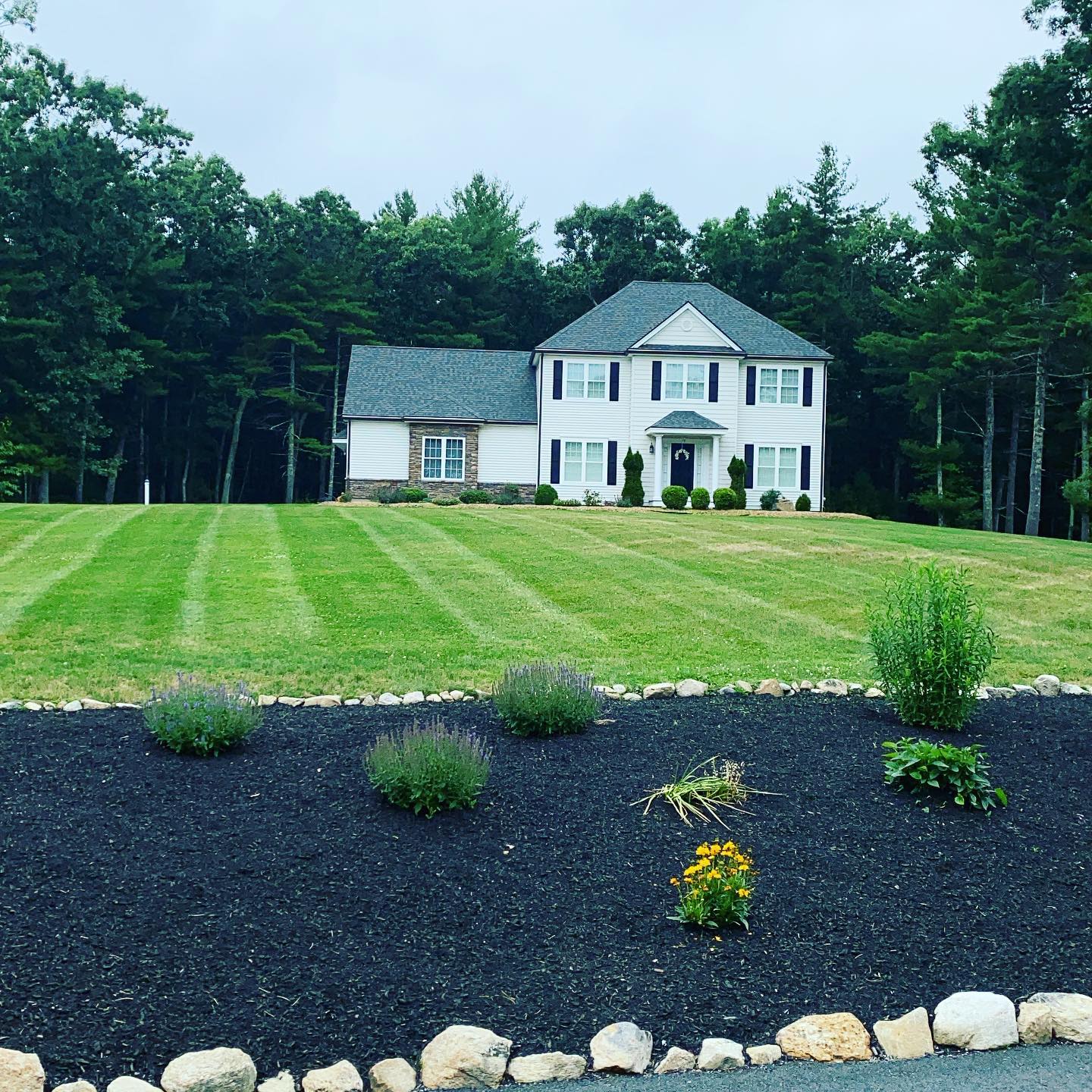 A large white house sits on top of a lush green hillside surrounded by trees.