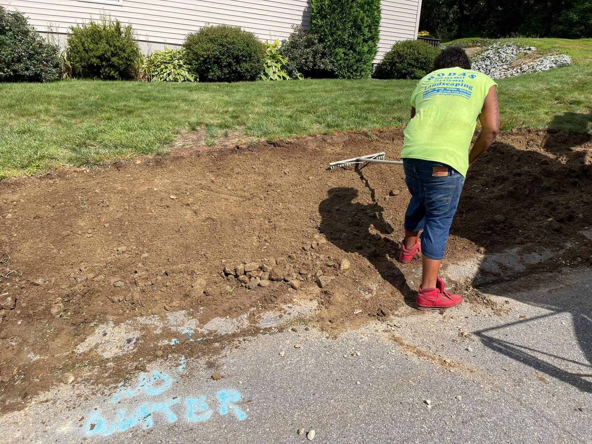 A man is digging a hole in the dirt in front of a house.