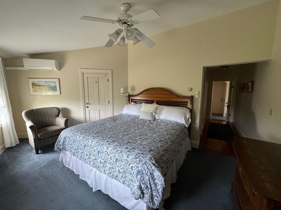 A bedroom with a bed , chair and ceiling fan