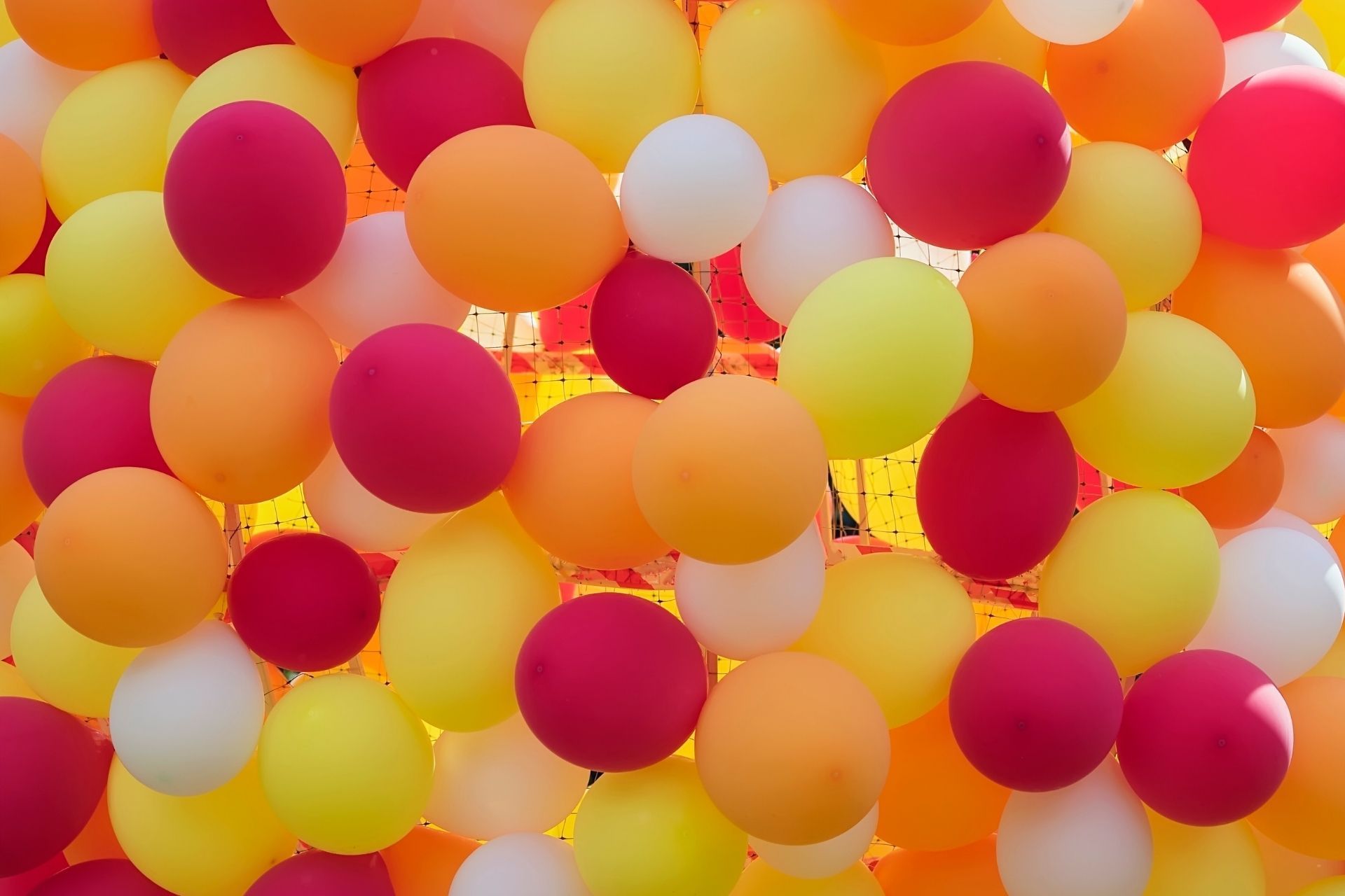 Palloncini colorati nelle tonalità del giallo, arancione, bianco e rosso, strettamente ammassati tra loro.