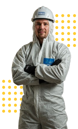 A man in a protective suit and hard hat is standing with his arms crossed.