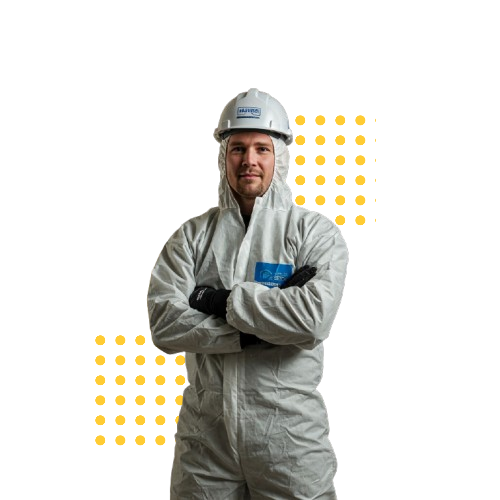 Person scrapes excess insulation from a floor in a room with a window, ladder, and partially insulated walls.