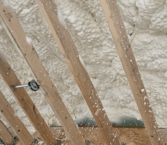 Wooden rafters with expanding foam insulation filling the space.